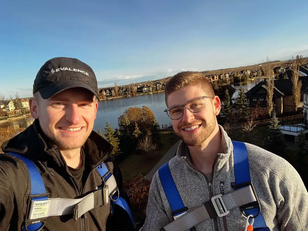 Co-owners in safety harnesses with cityscape and houses in background.