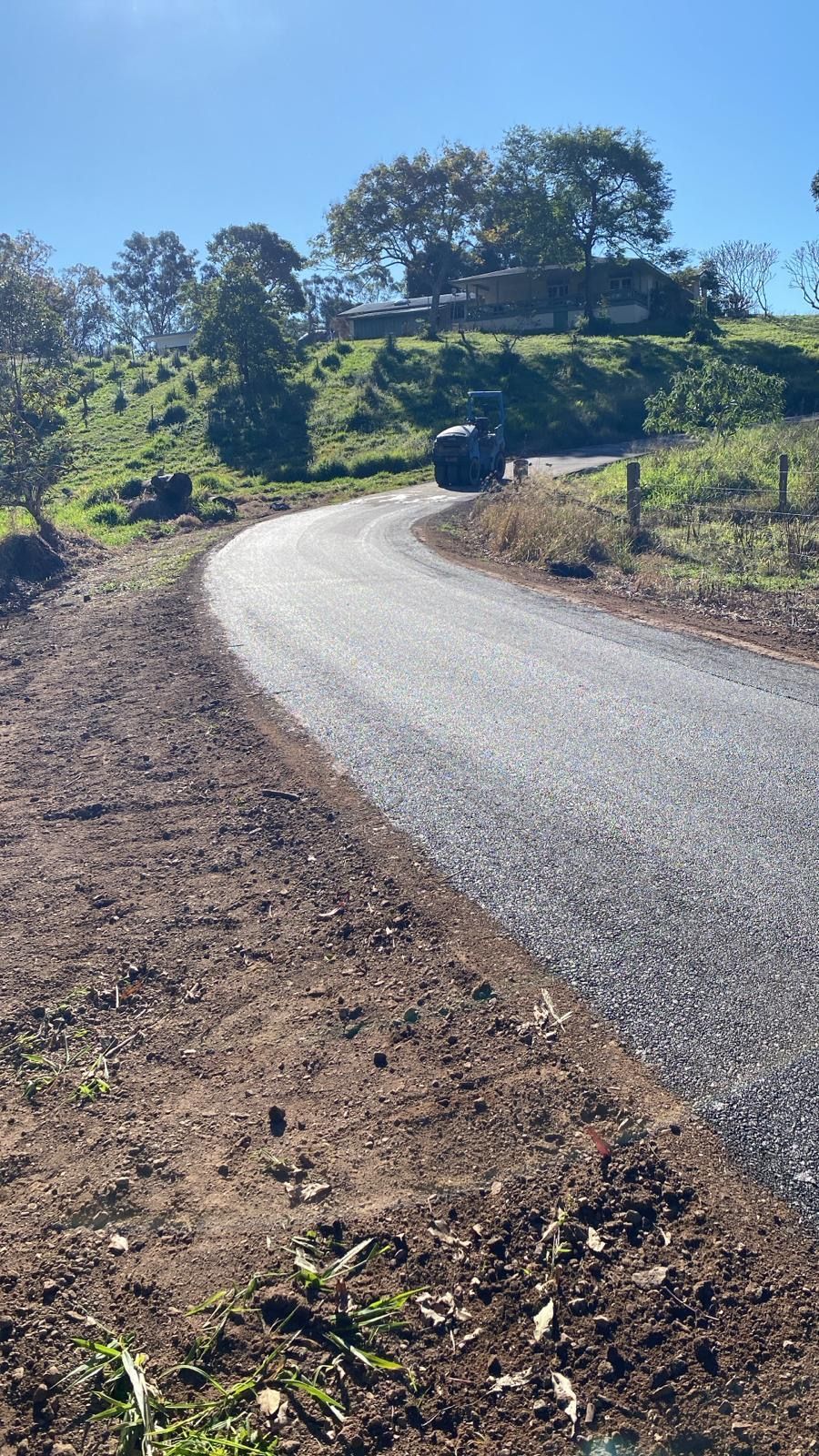 A Car Is Driving Down A Curvy Road In The Countryside — Roll Formed Driveways in Yandina, QLD