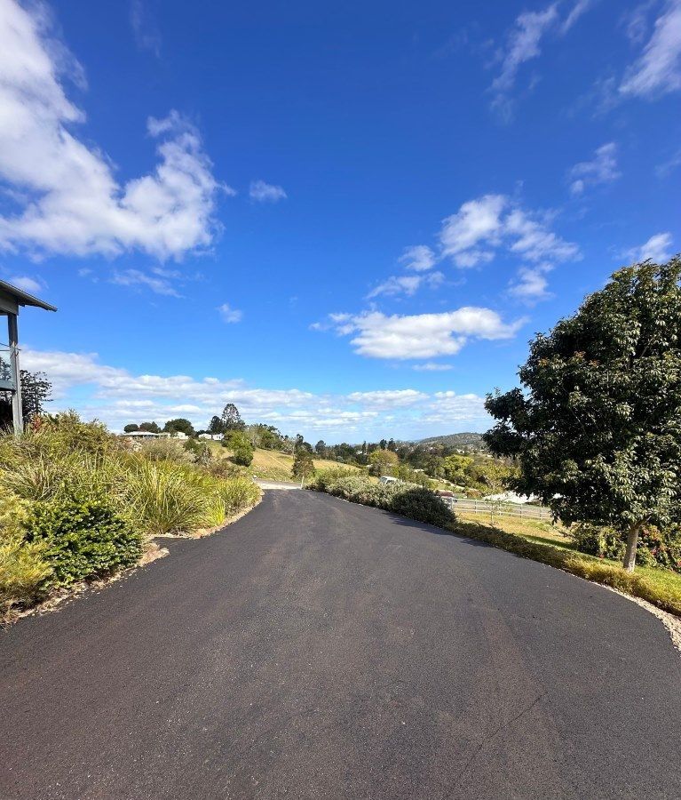 A Road With Trees On Both Sides And A Blue Sky — Roll Formed Driveways in Maryborough, QLD