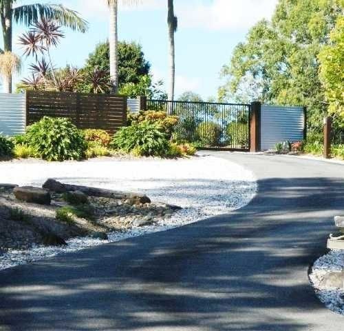 A Road with a Fence and Trees on the side of it — Roll Formed Driveways in Yandina, QLD