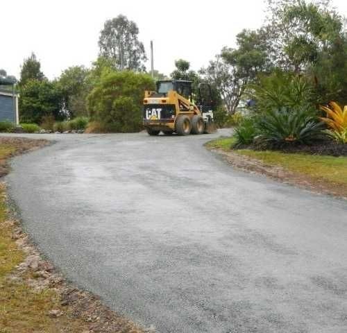 A cat Bulldozer is Driving down a curvy road — Roll Formed Driveways in Yandina, QLD