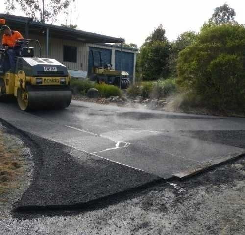 A Man on A Roller Compacting Asphalt — Roll Formed Driveways in Yandina, QLD