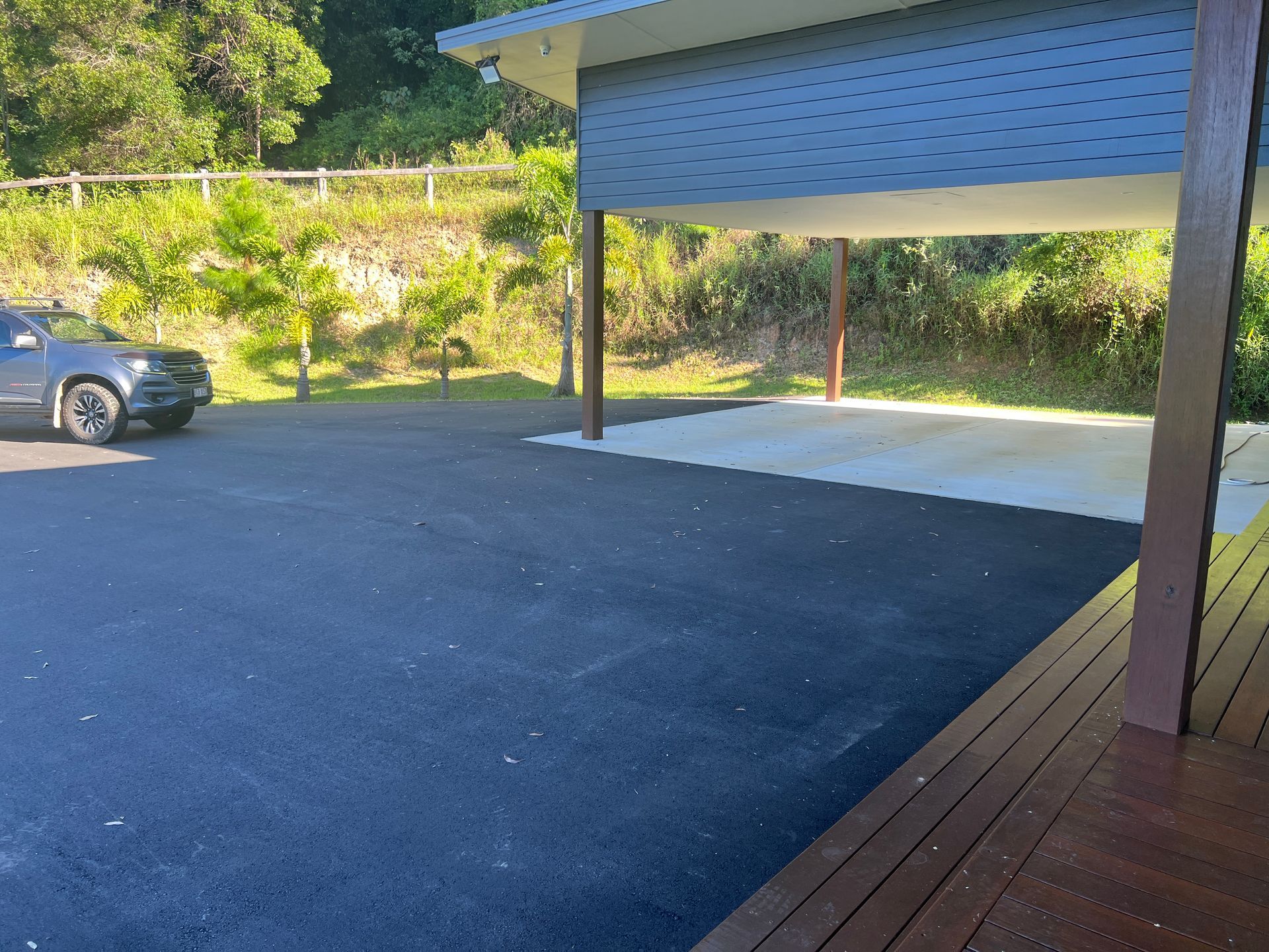 A Car Is Parked In A Parking Lot Next To A House — Roll Formed Driveways in Sunshine Coast, QLD