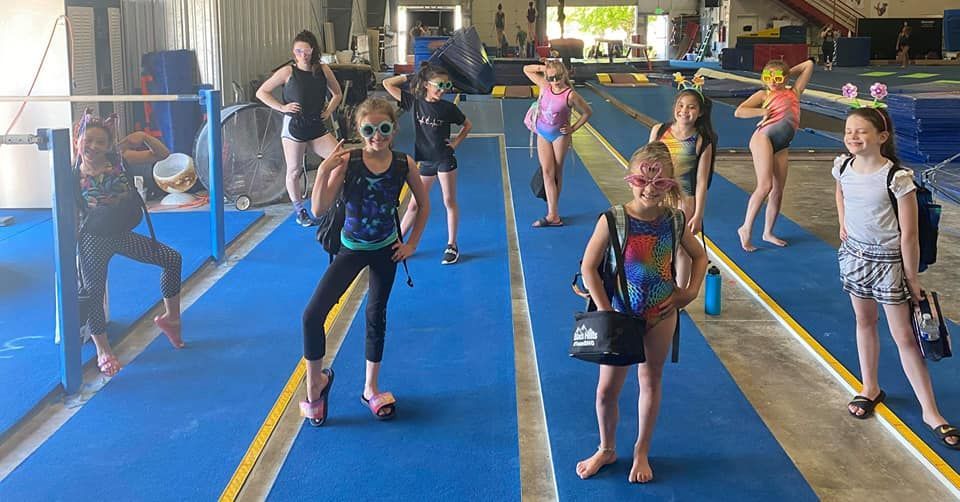 A group of young girls are standing on a blue mat in a gym.