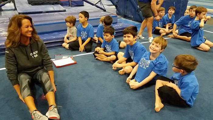 A woman is sitting on the floor talking to a group of children.