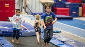 A group of children are jumping on a trampoline in a gym.