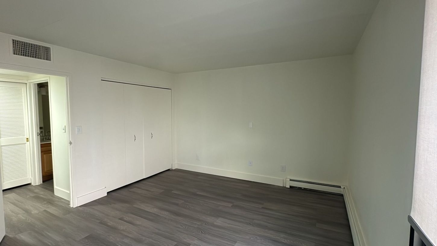 An empty living room with hardwood floors and white walls.