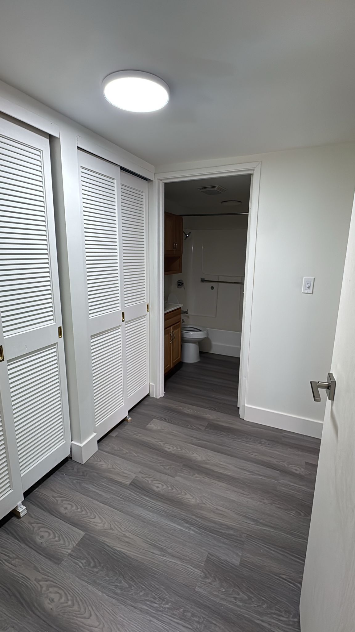 A hallway with sliding doors leading to a bathroom and a toilet.