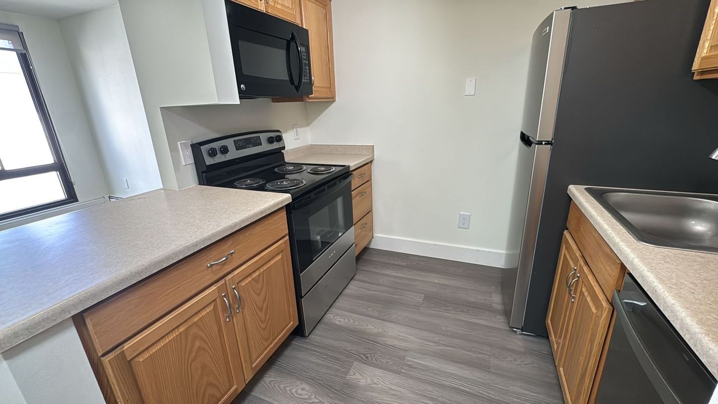 A kitchen with a stove , microwave , refrigerator and sink.