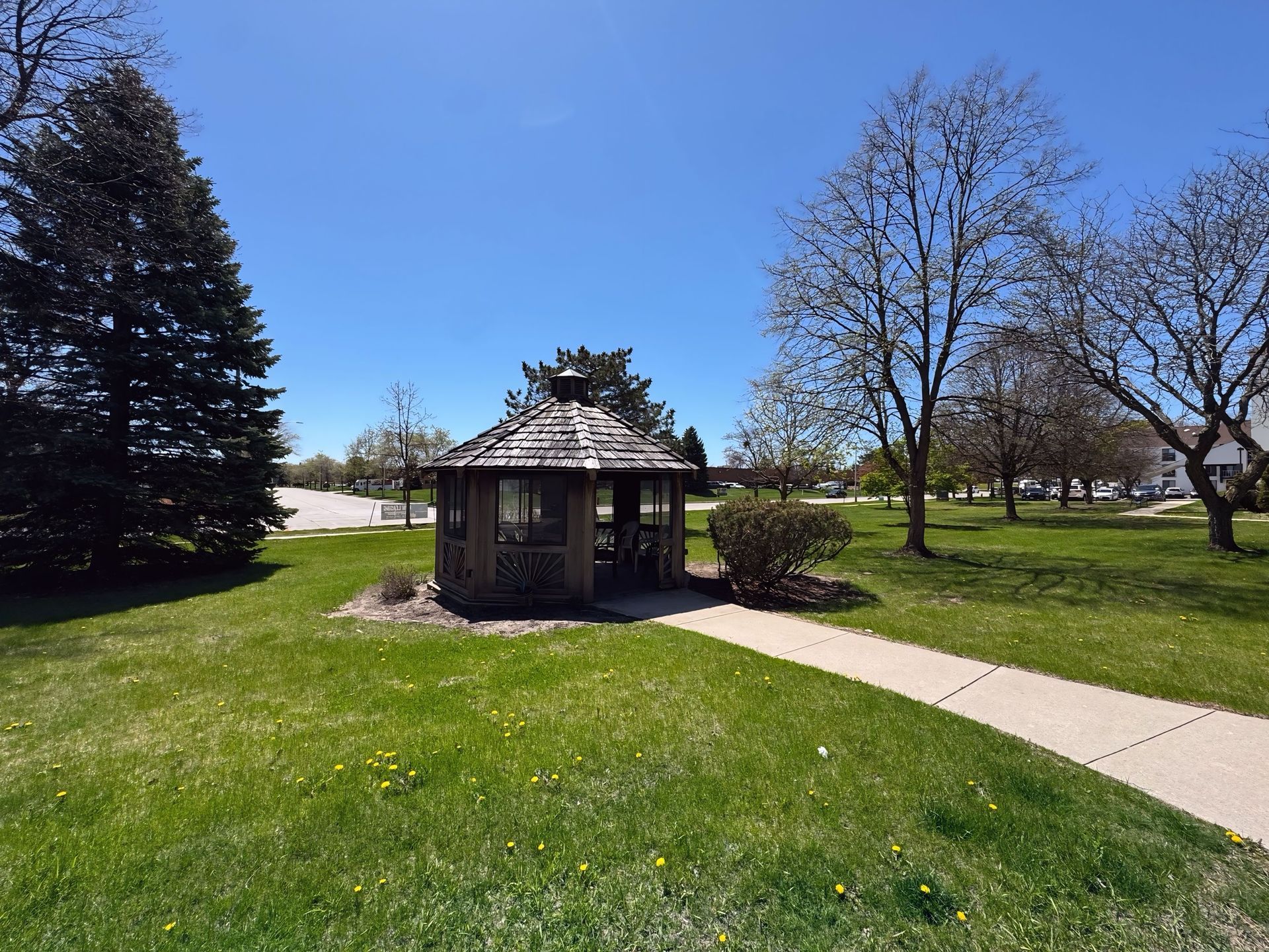 A gazebo in the middle of a park with trees in the background.