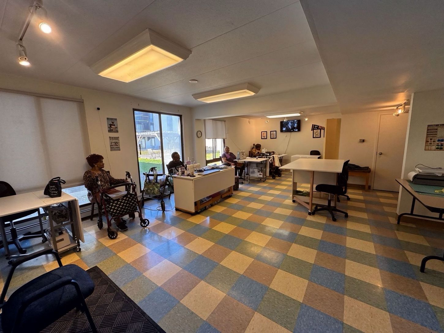 A group of people are sitting at tables in a room with a checkered floor.