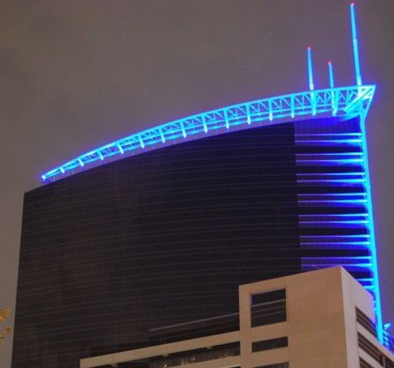 Modern white office building with large glass windows reflecting trees and sky.