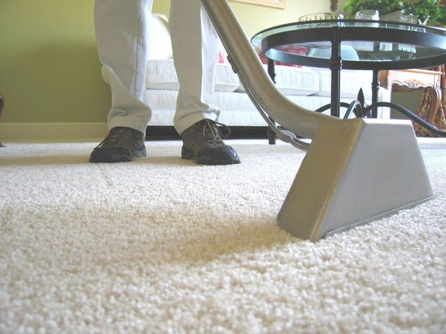 A person is using a vacuum cleaner on a white carpet