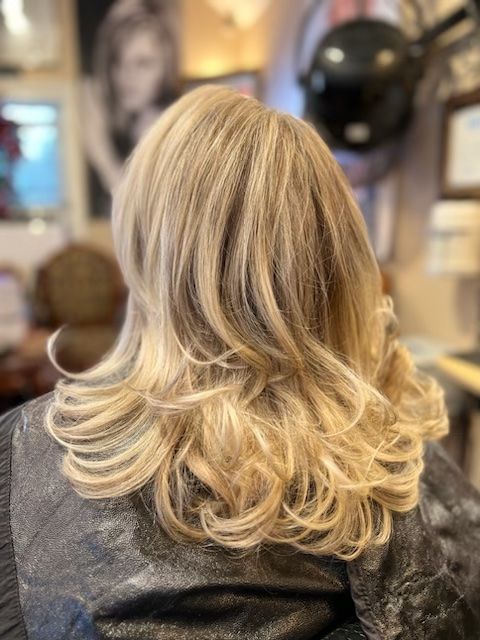 A woman with blonde hair is sitting in a chair in a salon.