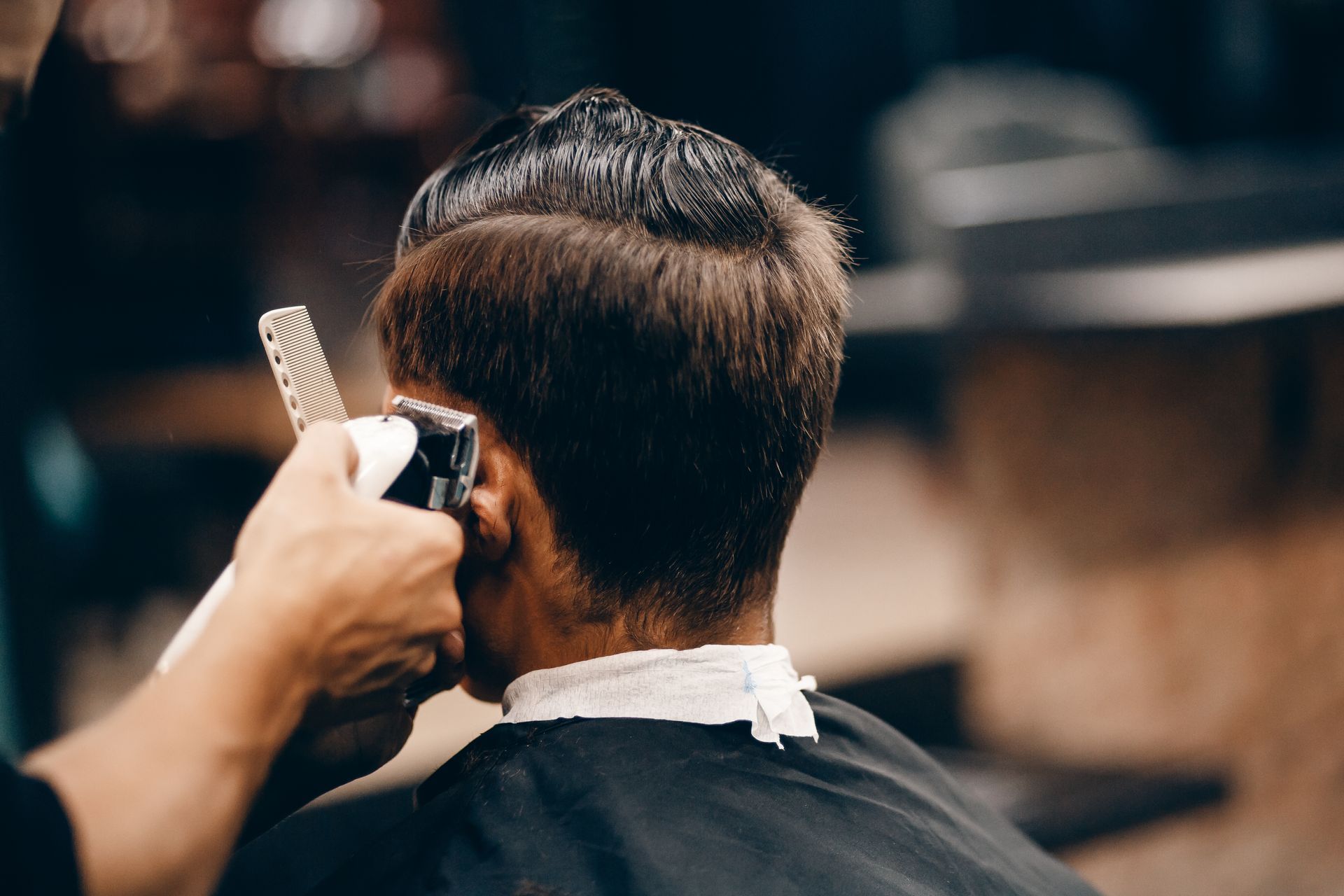 A man is getting his hair cut by a barber in a barber shop.