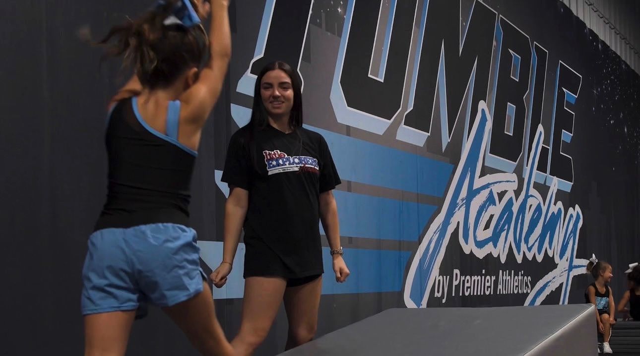 A young girl is climbing a rope in a gym