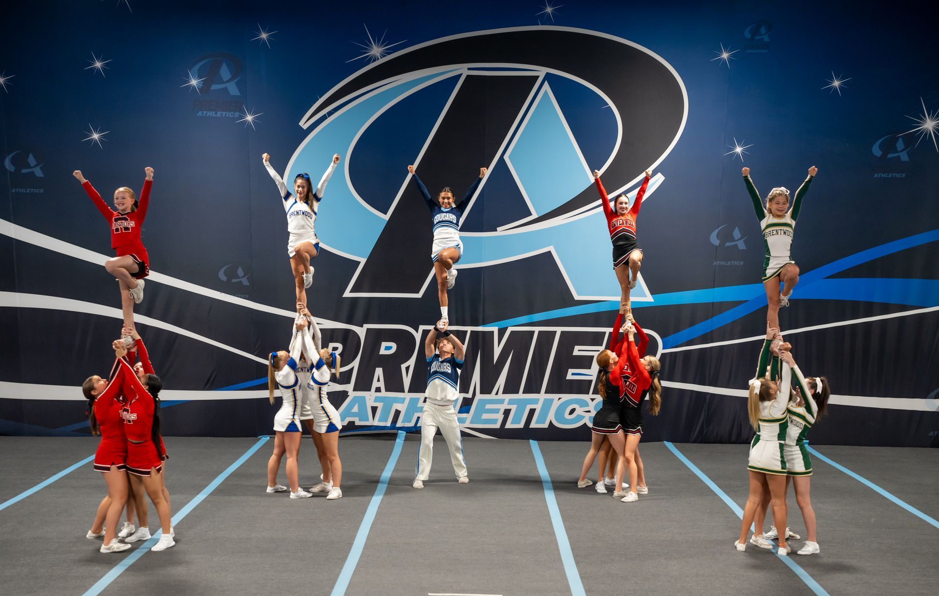 A group of cheerleaders are performing in front of a premier athletic logo.