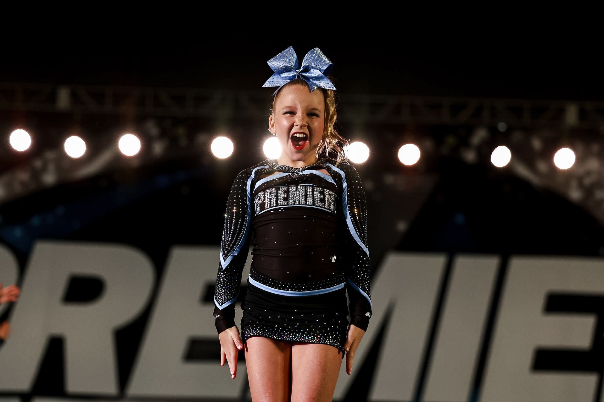 A group of cheerleaders are posing for a picture on a stage.