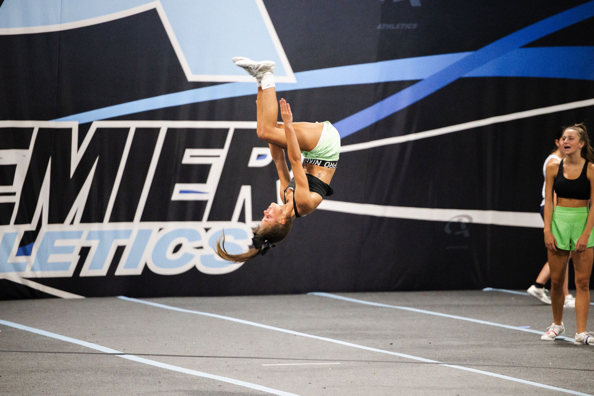 A little girl wearing a pink tank top that says cheer