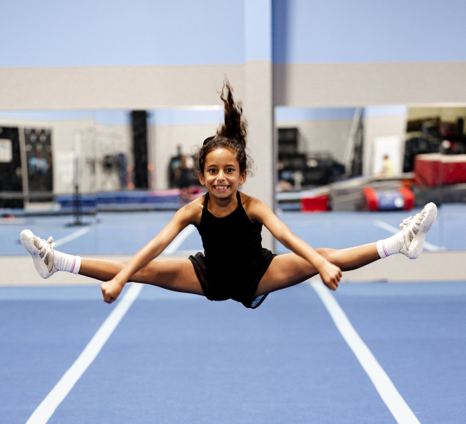 A cheerleader is standing in front of a premier athletics logo.
