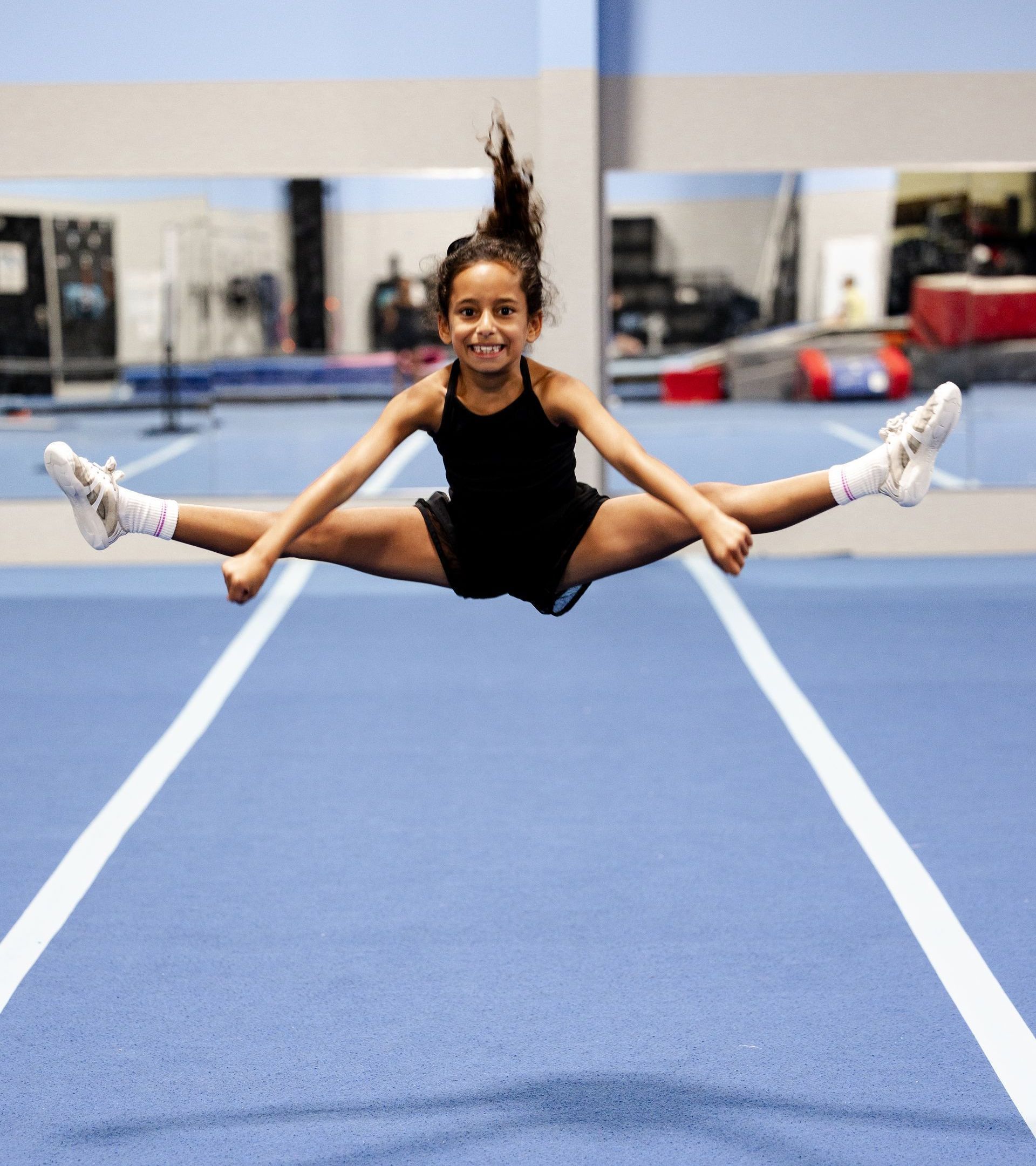 A young girl is climbing a rope in a gym