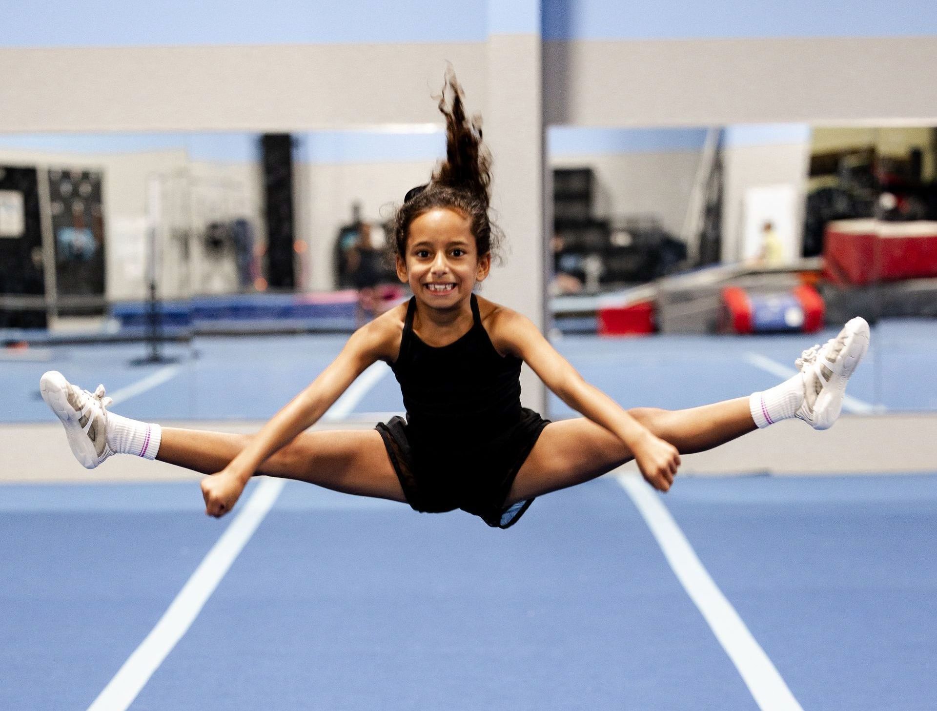A young girl is climbing a rope in a gym