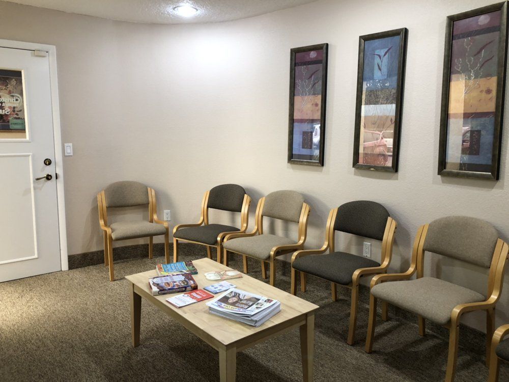 Waiting room with chairs, a table, and artwork on the wall.