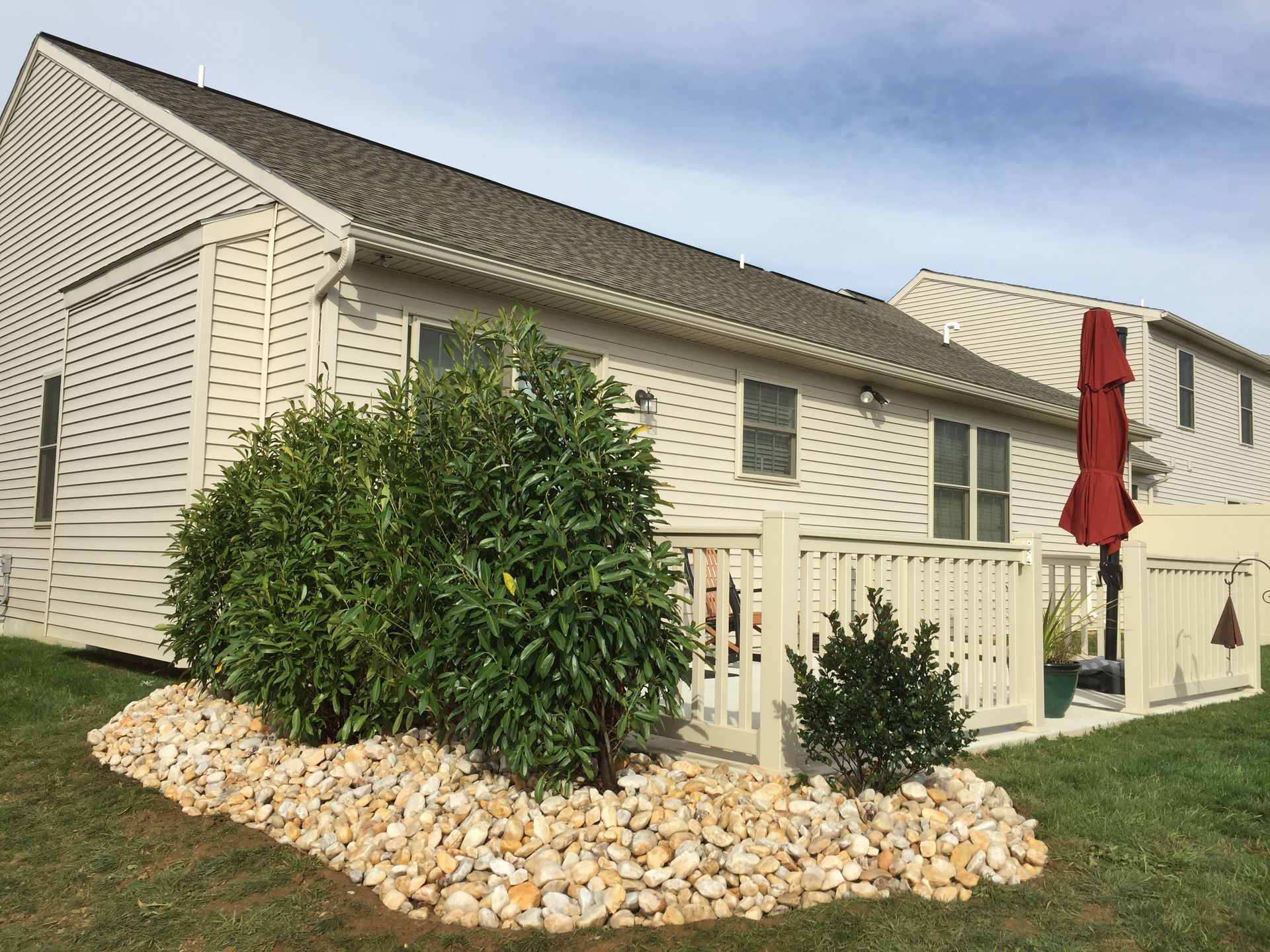 A white house with a white fence and a red umbrella in front of it.