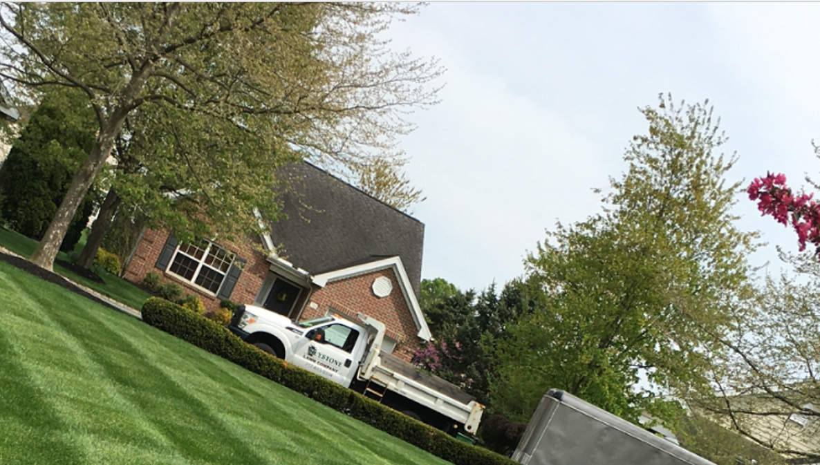 A white truck is parked in front of a brick house.