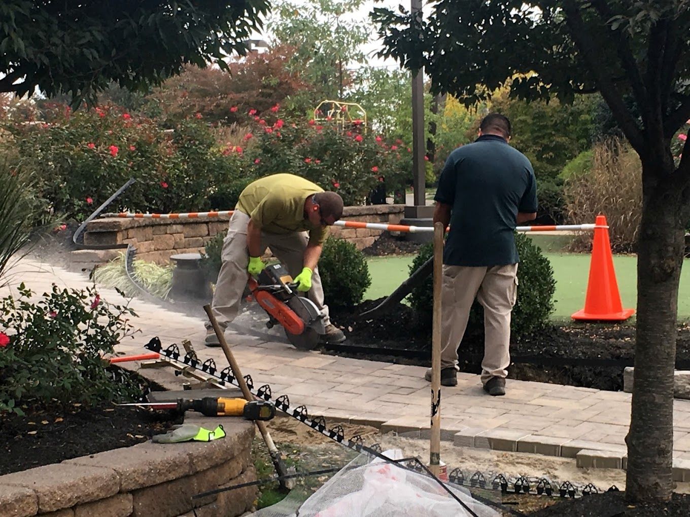 A man is using a chainsaw to cut a brick walkway.