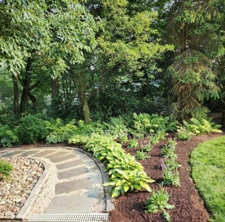 A stone walkway in a garden surrounded by trees and bushes.