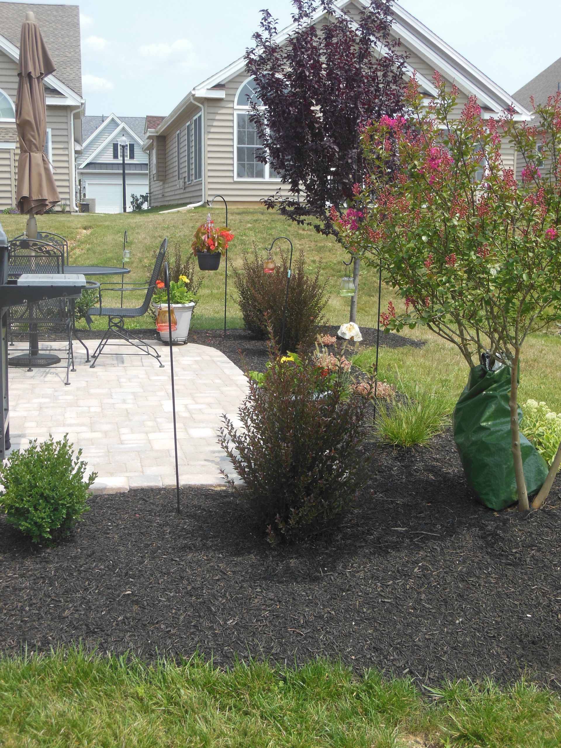 A patio with a table and chairs and flowers in front of a house