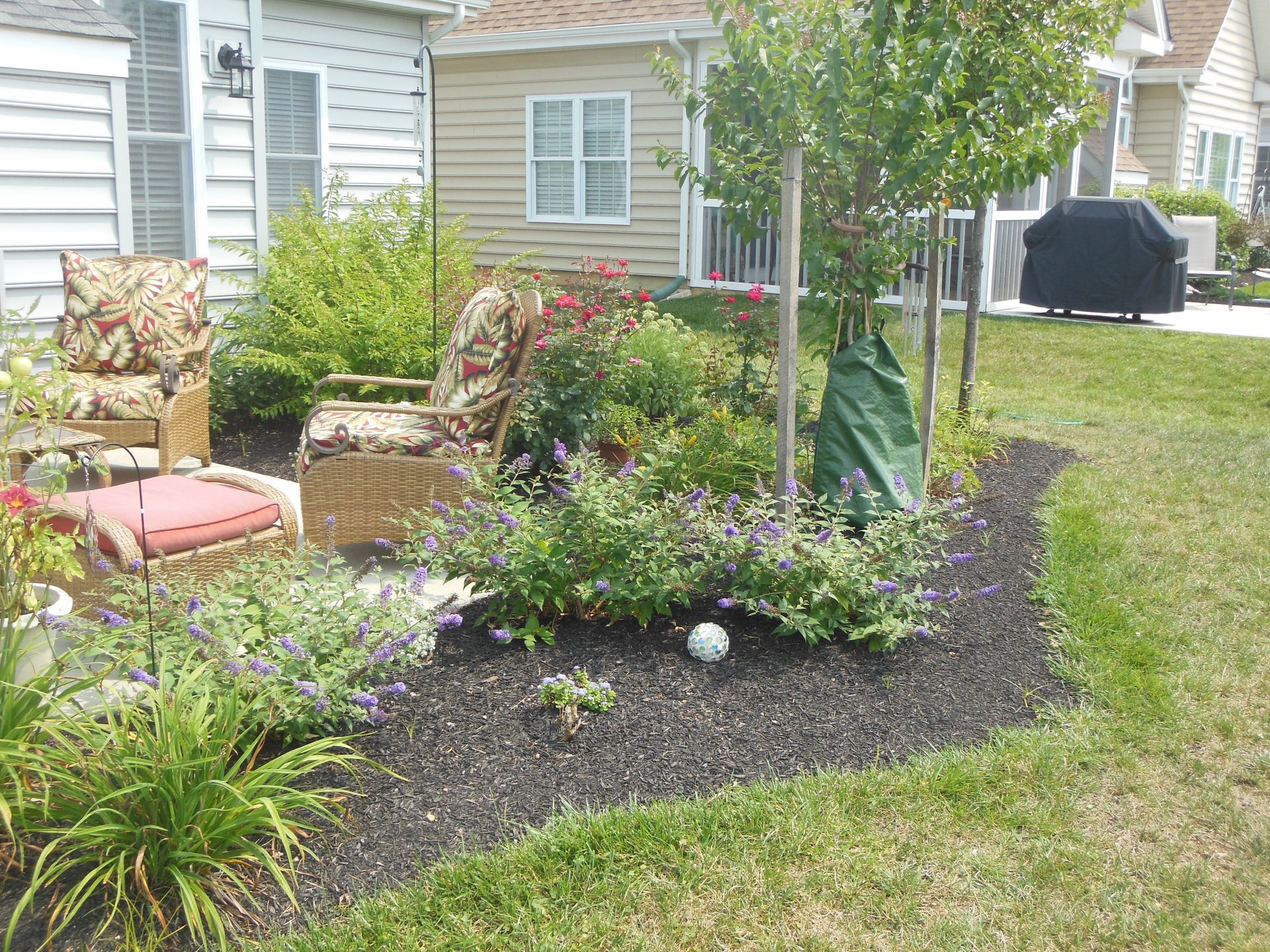 A lawn with a chair and a table in front of a house