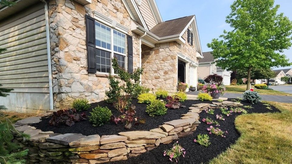 A stone house with a lush green lawn in front of it.