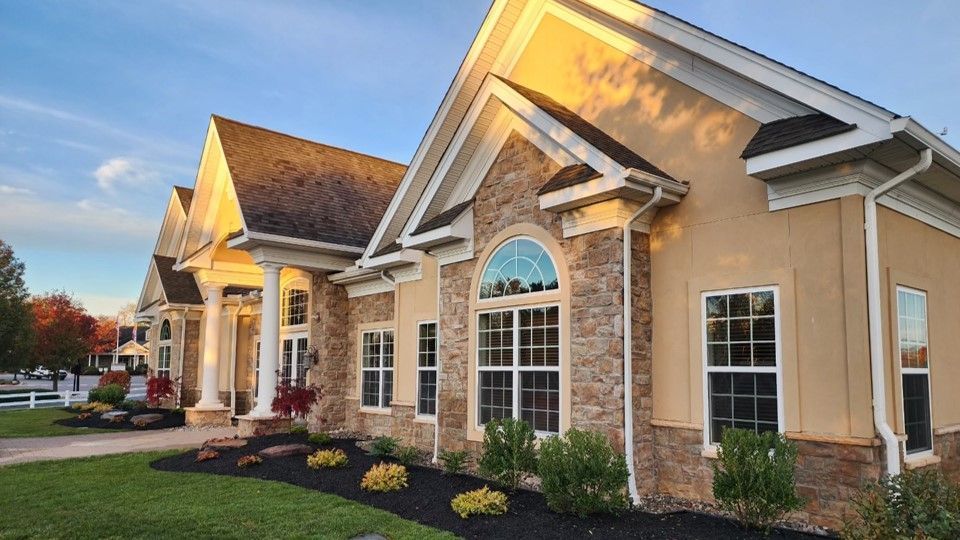 A large house with a lot of windows is sitting on top of a lush green lawn.