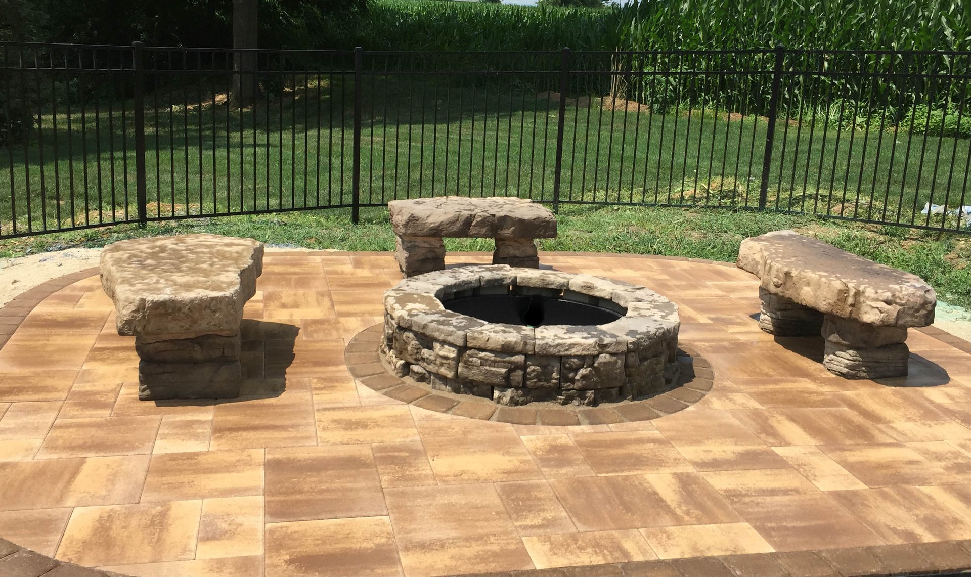 There is a fire pit in the middle of the patio with benches around it.