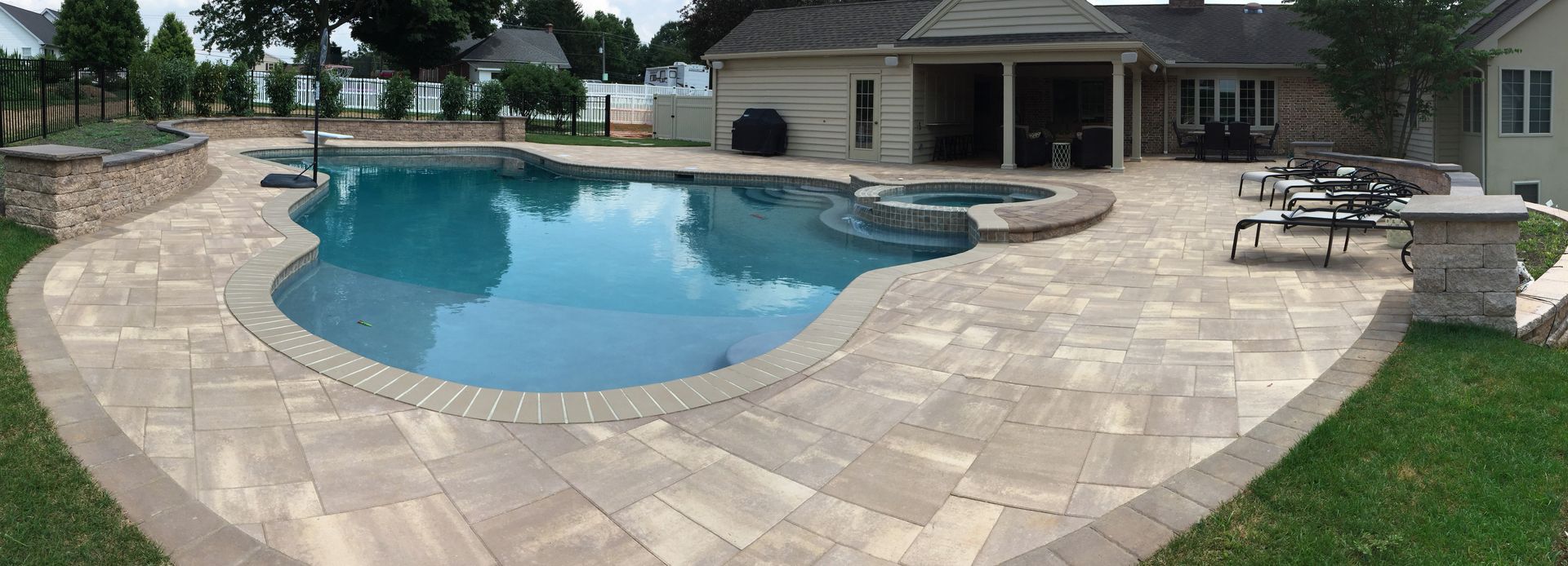 There is a large swimming pool in the backyard of a house.
