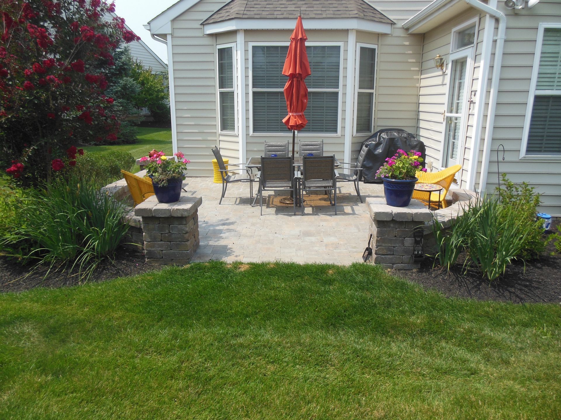 A patio with a table and chairs and an umbrella in front of a house