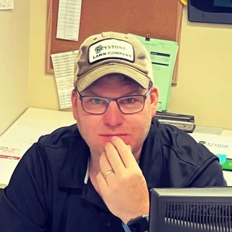 A man wearing a hat that says keystone lawn company