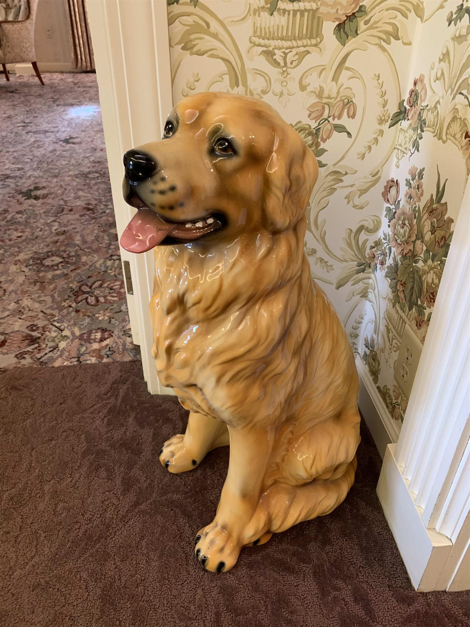 A statue of a golden retriever dog is sitting next to a door.