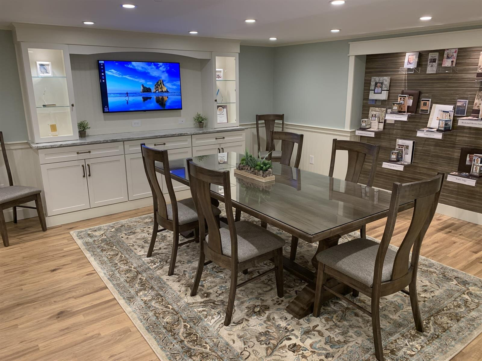 A dining room with a table and chairs and a television on the wall.