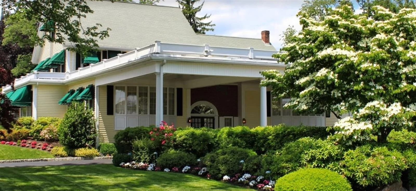 A house with a large porch and a lush green lawn