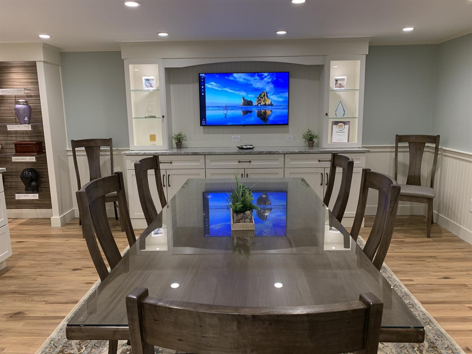 A dining room with a table and chairs and a flat screen tv