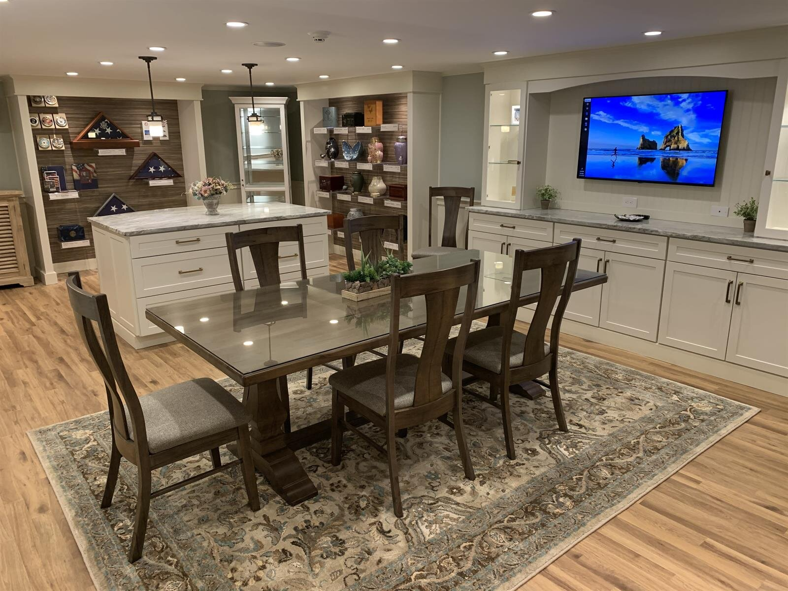 A dining room with a table and chairs and a television on the wall.