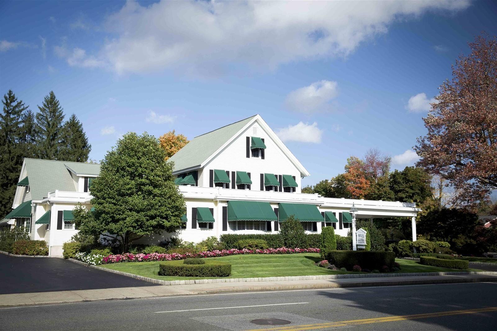 A large white house with green awnings on the windows