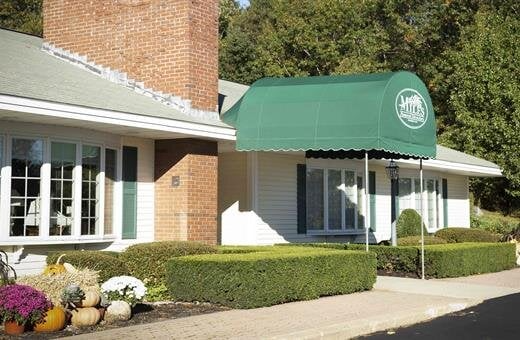 A white house with a green awning over the entrance