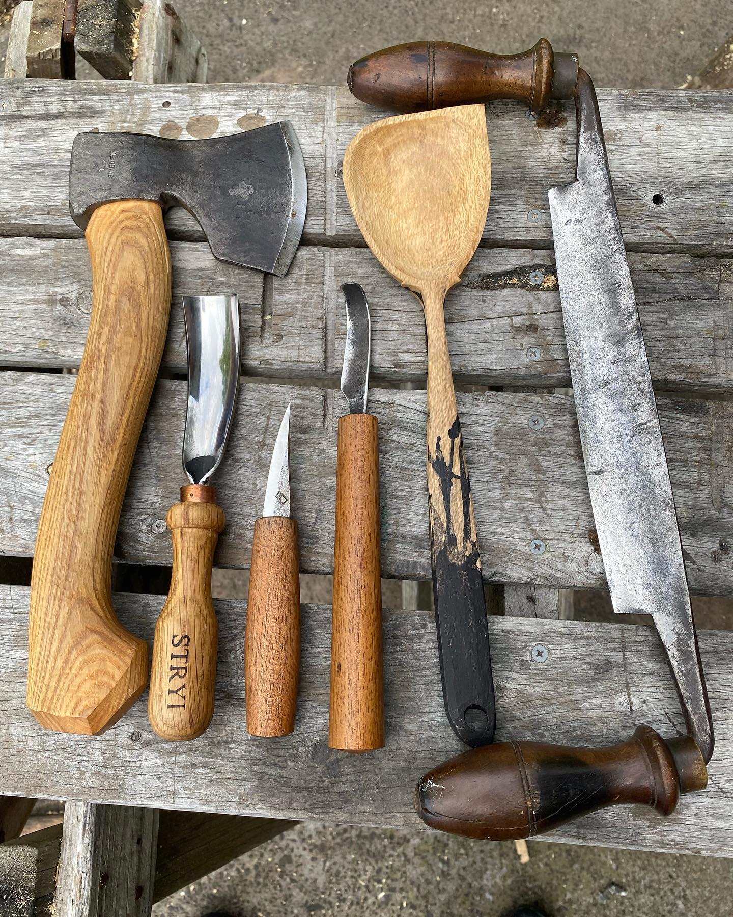 A group of wood carving tools are sitting on a wooden table.