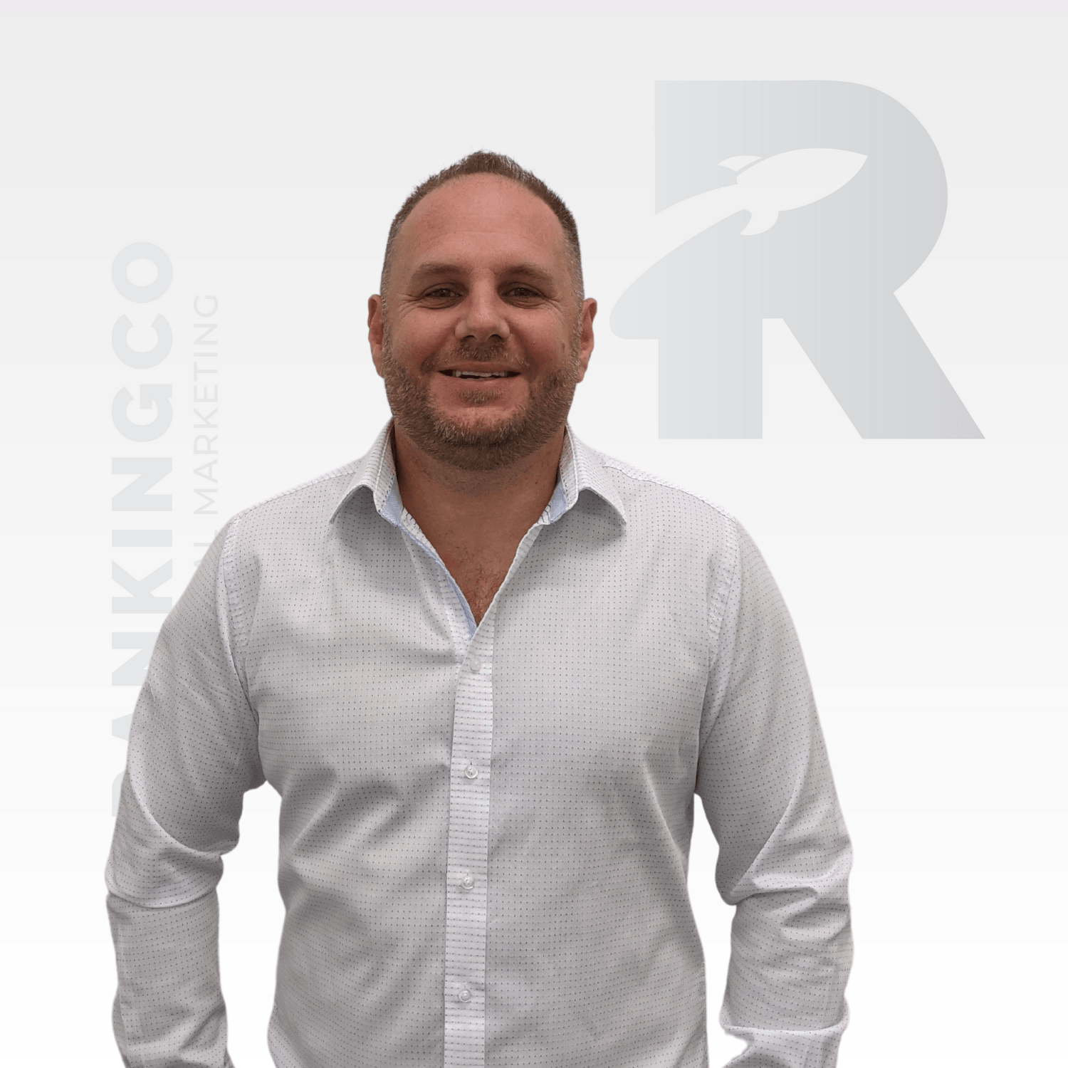 A man in a white shirt is standing in front of a r logo