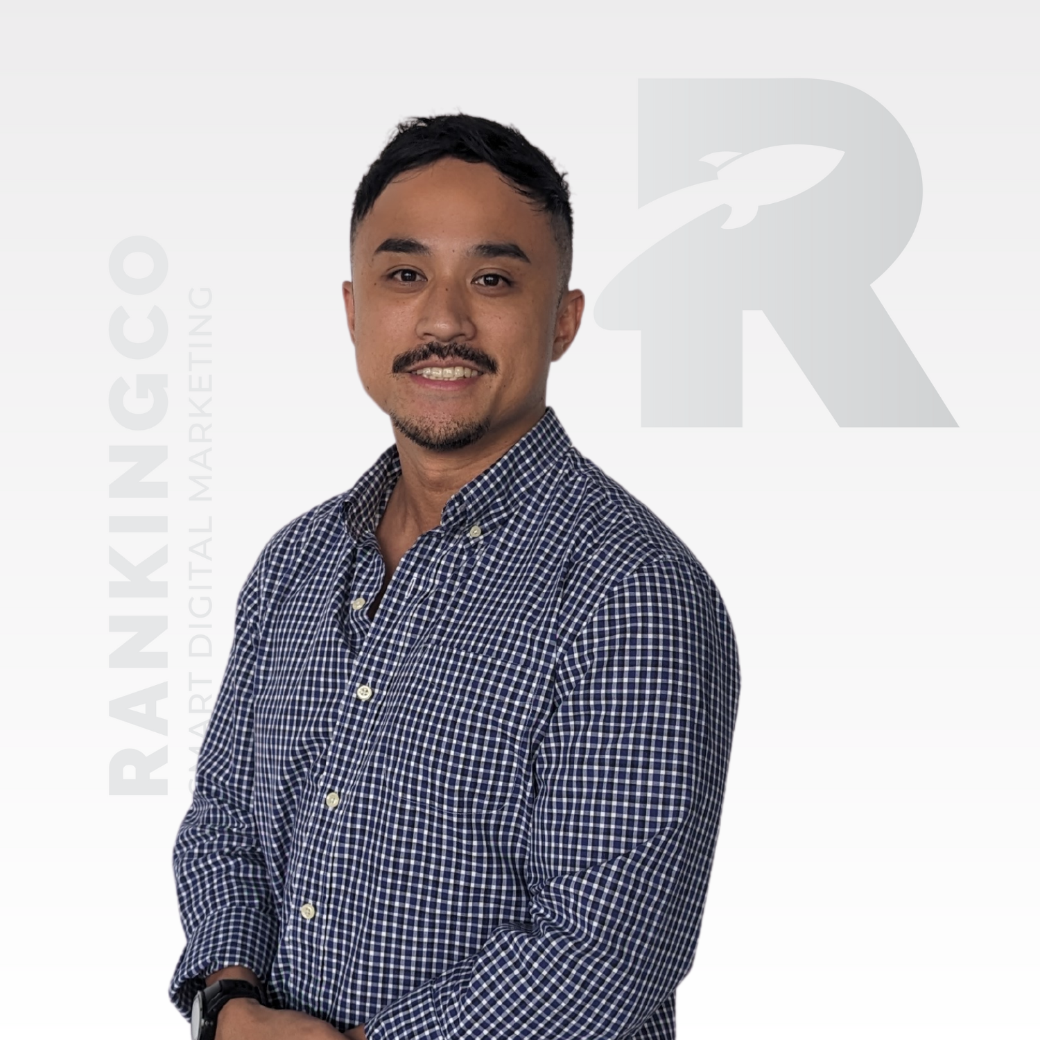 A man in a plaid shirt is standing in front of a logo for ranking co