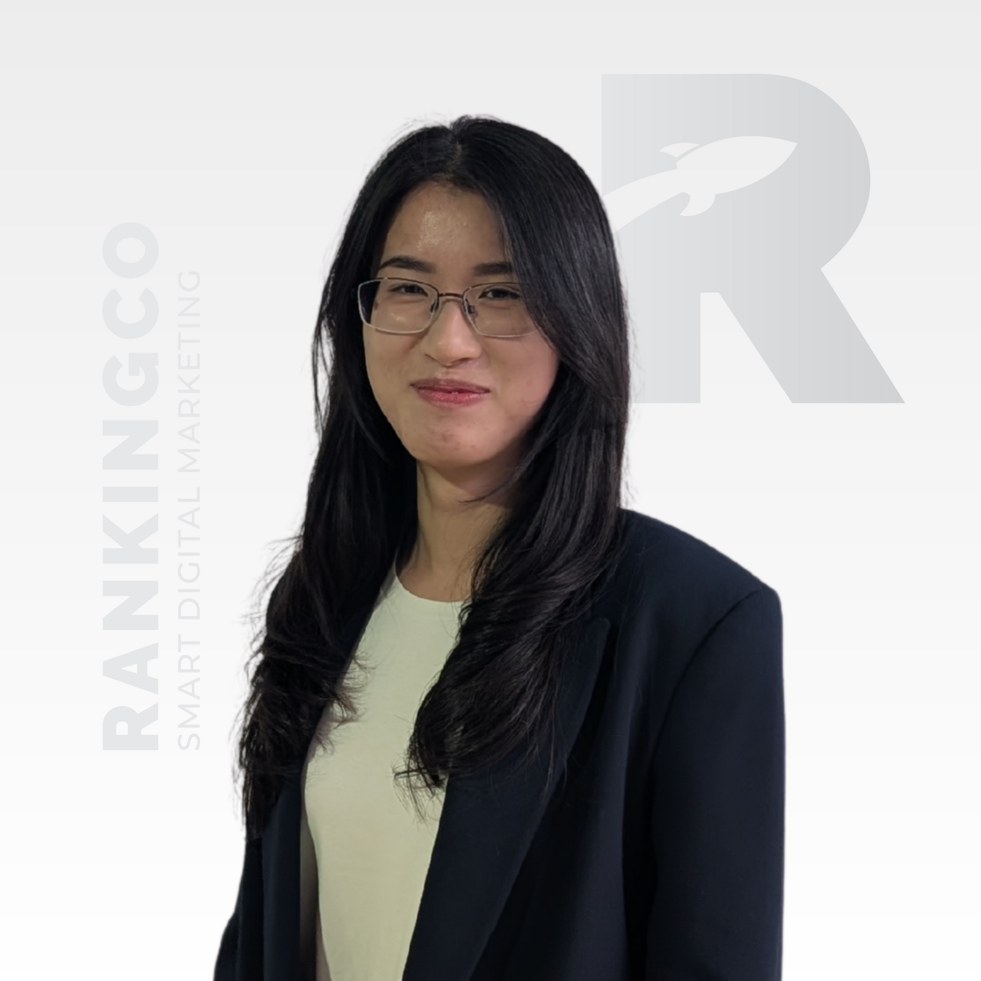 A woman wearing glasses and a black jacket is standing in front of a sign that says ranking co